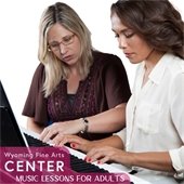 two women sitting at a piano one is teaching the other how to play the piano