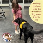 image of a girl letting a black lab sniff her hand