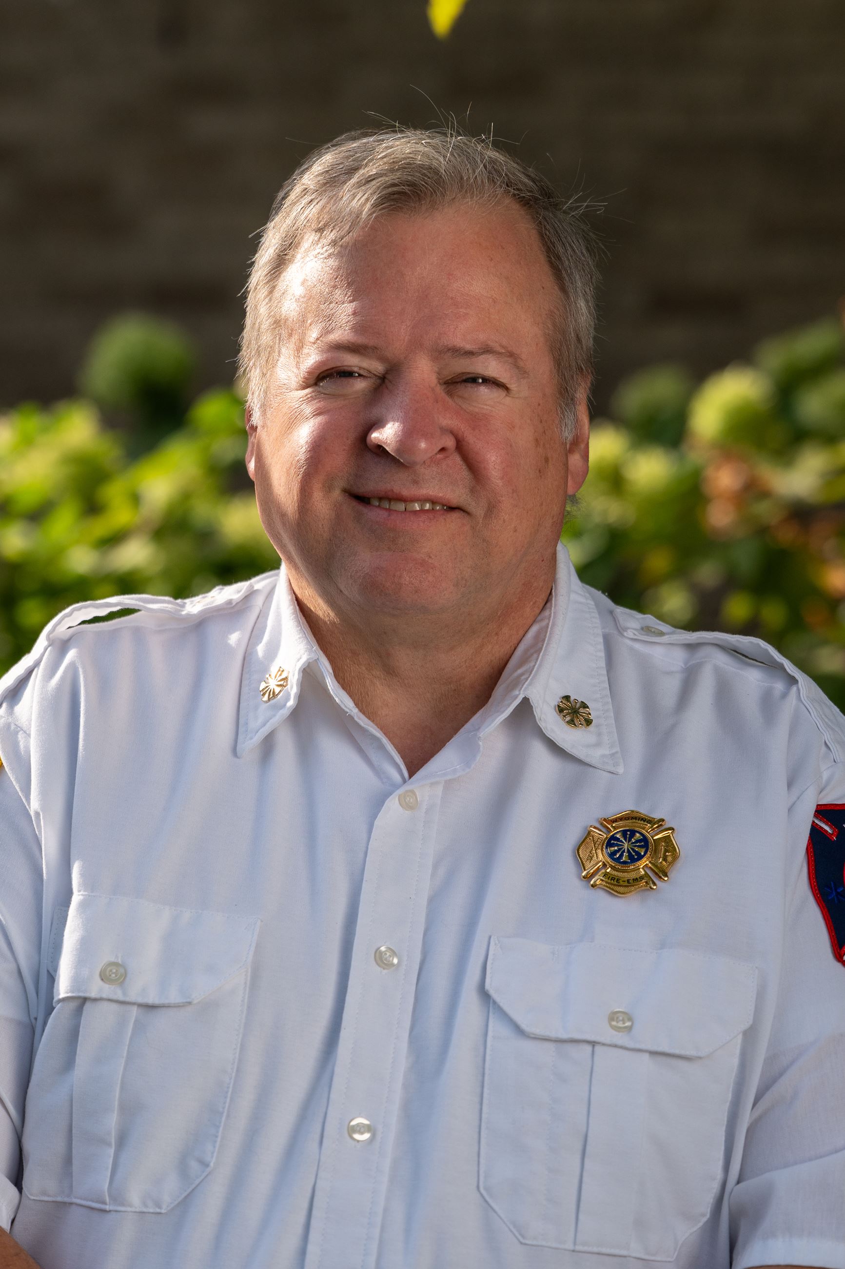 man wearing white button down shirt with fire department pin